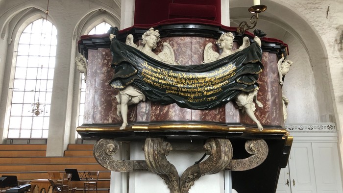 Ein prächtiger, verzierter Altar in einer Kirche mit Statuen und Inschriften.