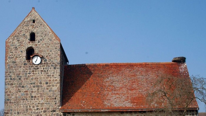 Alte Kirche mit Turm und Zifferblatt unter blauem Himmel