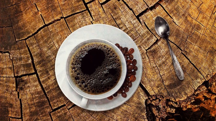 En kop kaffe og et lille spade på en træskive