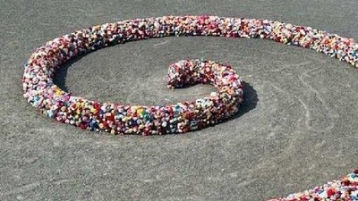 Bunte Perlen bilden ein kompliziertes Spiralmuster auf einer sandigen Oberfläche.