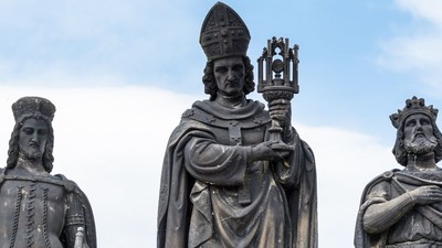Bronzestatuen zeigen einen Bischof und zwei gekrönte historische Figuren, die zeremonielle Gegenstände vor einem Himmelshintergrund halten.