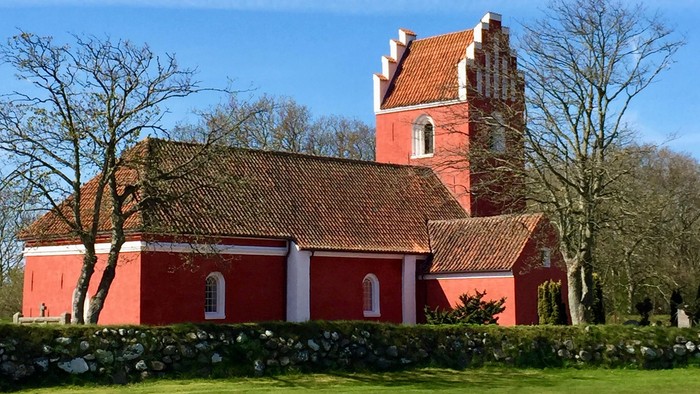 Rødt kirke med tårn og tagtegn i træ.