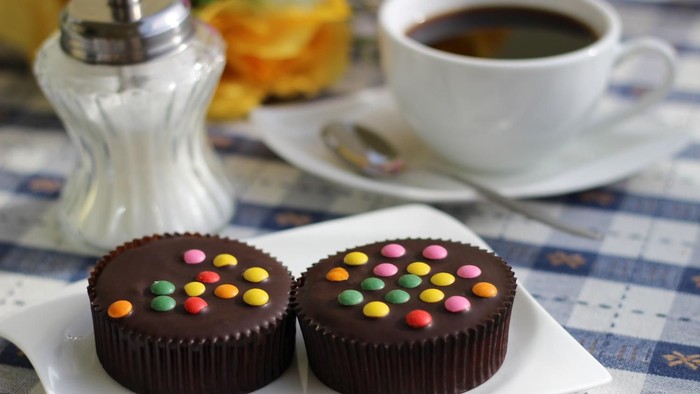 Bild von einer Kaffeetasse und zwei Muffins mit Schokolinsen