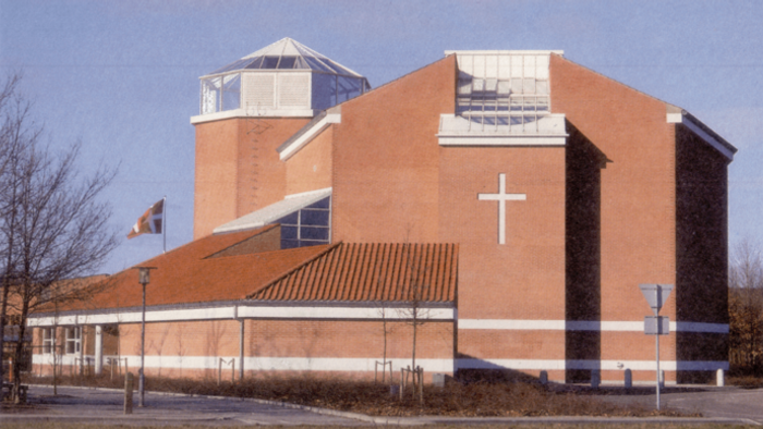 En stor, rød kirke med et stort kors på fasaden og en tårnagtig struktur på taket