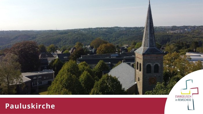 Luftaufnahme der Pauluskirche, umgeben von einer malerischen, bewaldeten Stadtlandschaft.