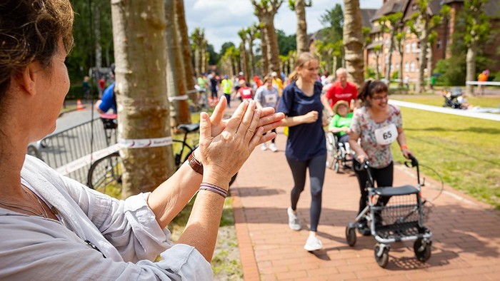 Läuferinnen zu Fuß und mit Rollator beim Run of Spirit. An der Seite wird Beifall geklatscht.