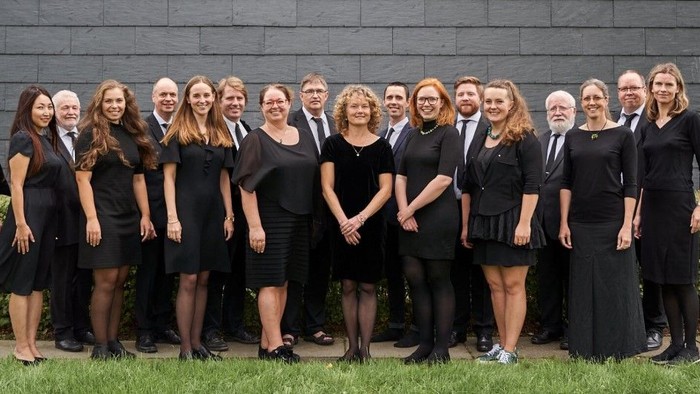 En gruppe professionelle kvinder i formelt tøj står sammen udendørs.