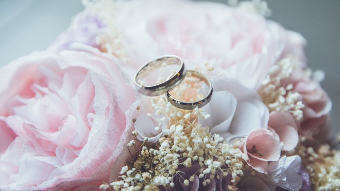 Zwei goldene Ringe auf rosa Blumen.