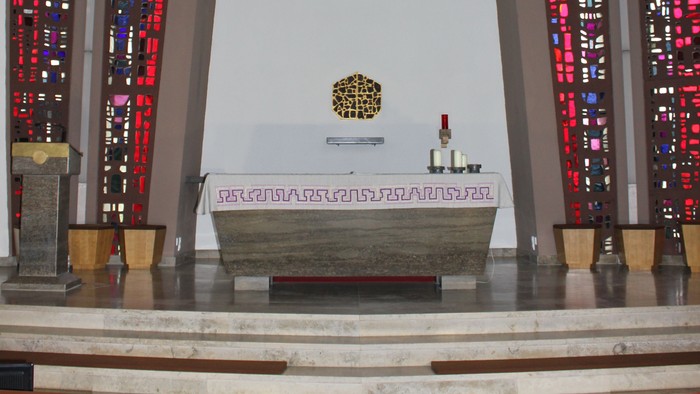 Die Kirche mit Altarraum, Kreuz und buntem Glasfenster