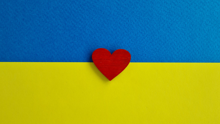Et rødt hjerte placeret på en blå og gul baggrund, der ligner det ukrainske flag.