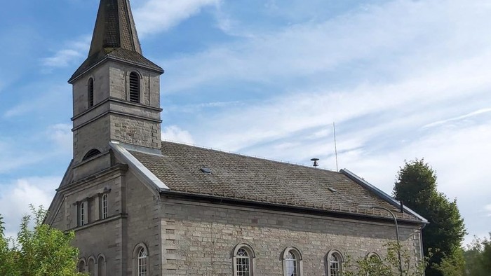 Steinerne Kirche mit hohem Turm und Rundbogenfenstern.