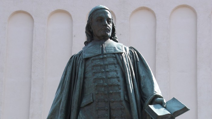 Die Bronzestatue eines Mannes mit Buch und Federkiel.