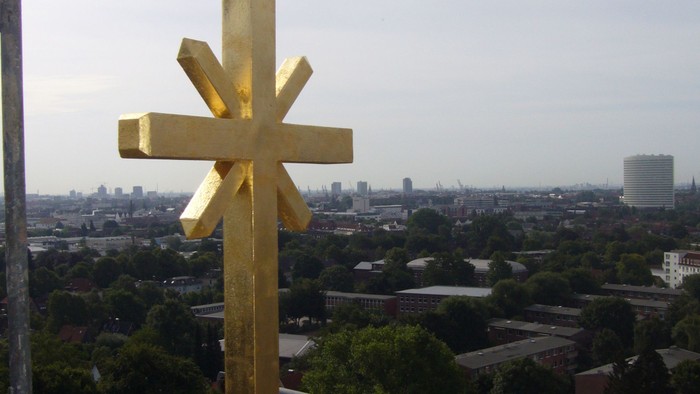 Ein hölzernes Kreuz steht auf einem Balkon mit Blick auf eine Stadt.