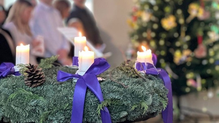 Julepynt med stearinlys og et træ, mennesker i baggrunden.