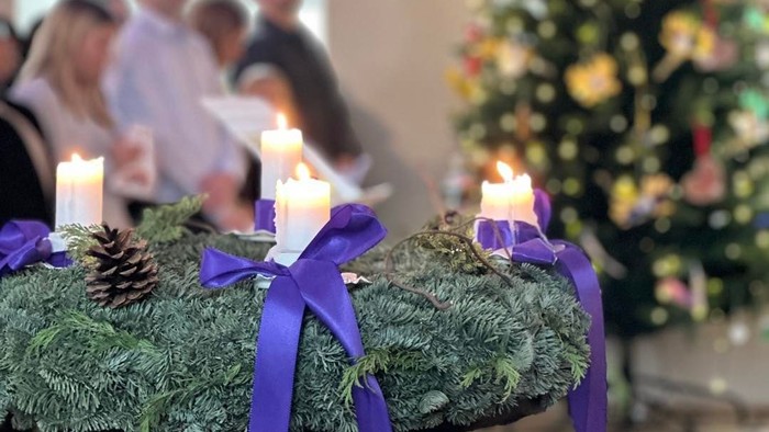 Julepynt med stearinlys og et træ, mennesker i baggrunden.