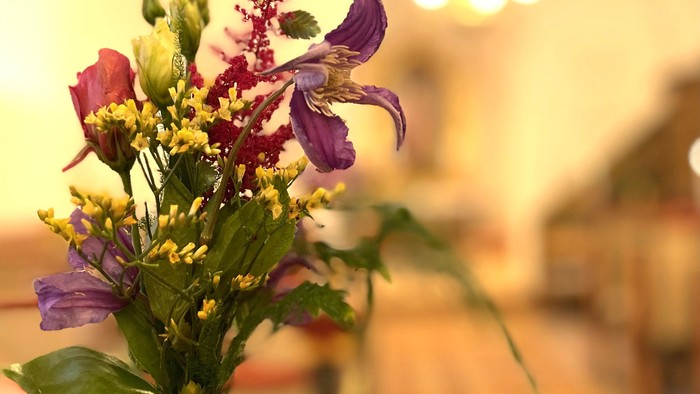 En vase med lilla og gule blomster på et bord
