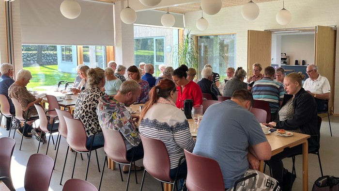 En gruppe af mennesker sidder i en lys og moderne lokalitet og deltager i en aktivitet.