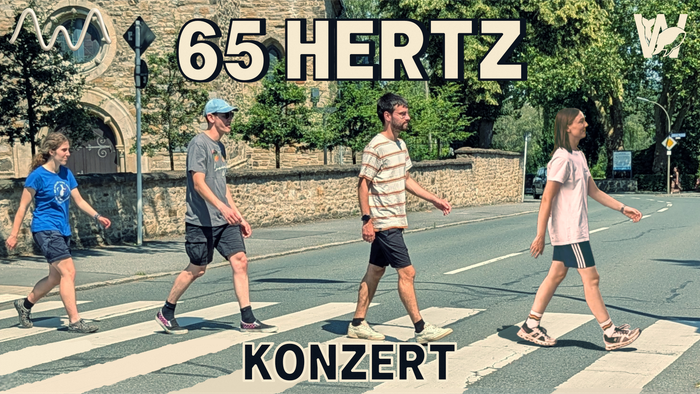 Menschen überqueren eine Straße auf einem Fußgängerüberweg während einer 65-Hertz-Konzert-Veranstaltung.