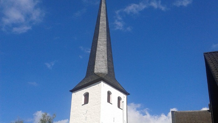 Weiße Kirche mit hohem Turm und blauen Himmel