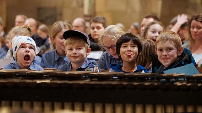 En gruppe børn og voksne ser opad i en kirke.