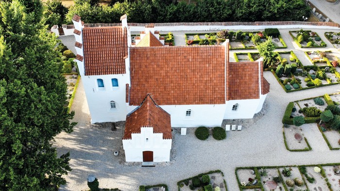 Luftfoto af en charmerende historisk bygning med røde teglstenstag og omgivet af anlagte haver.