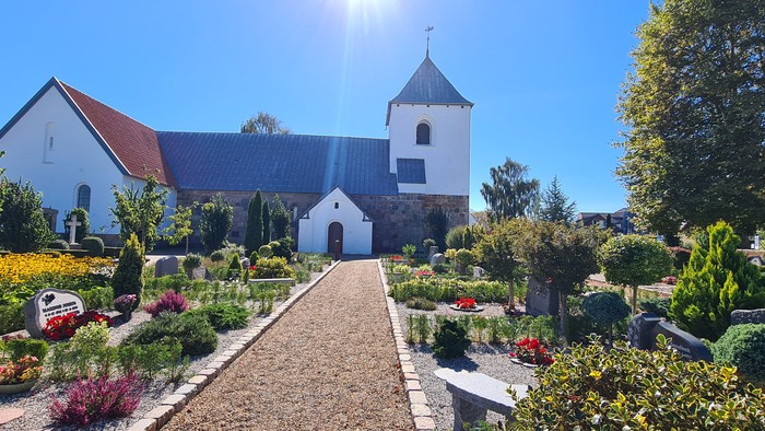 En smuk kirke med en have fuld af blomster og træer