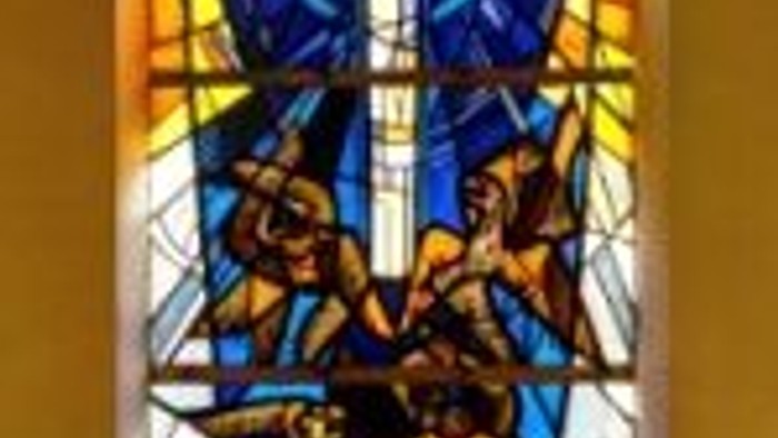Das Buntglasfenster zeigt eine religiöse Szene mit Jesus Christus am Kreuz