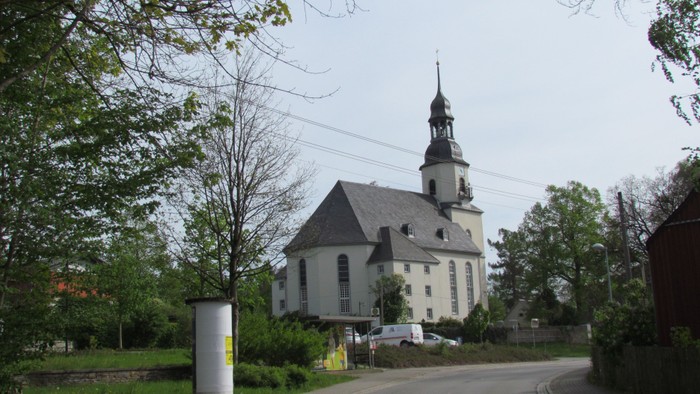 Kirchengelände mit weißem Kirchturm und umgebender Natur