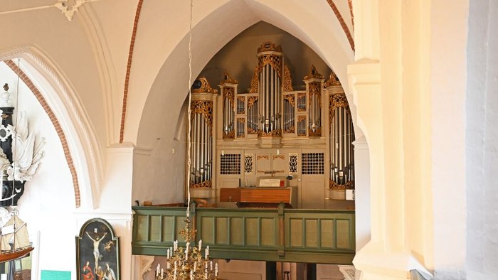 Orgel in einer Kirche, weißer Bogen, grüne Empore, Kronleuchter