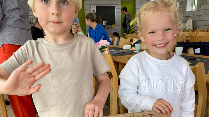 To børn holder stolt et skilt med klemmer og ting fra naturen.