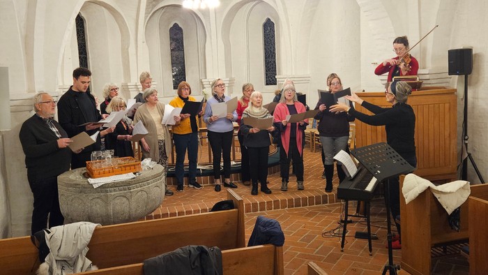 En kor sang i kirke med præst og musikere