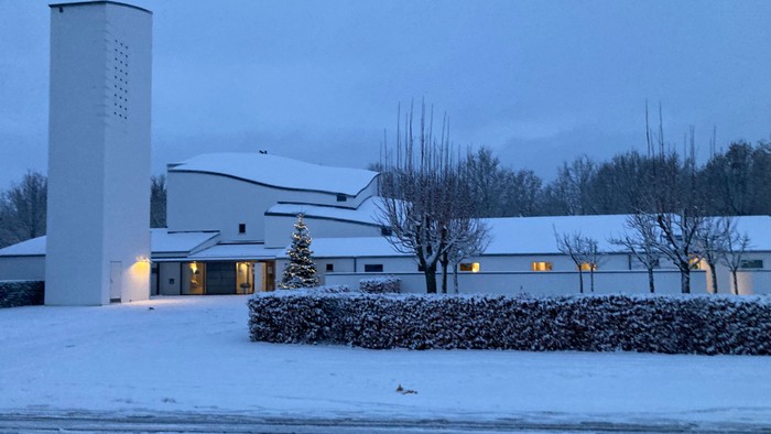 En snødekt kirke med højtårn og lyse vinduer.
