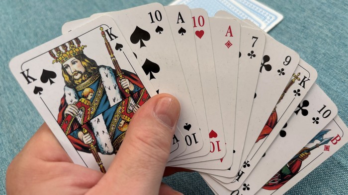 Eine Hand, die einen Fächer aus Spielkarten mit verschiedenen Werten und Farben hält.