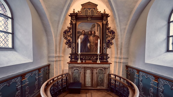 En indre kirkerum med alter og maleri.