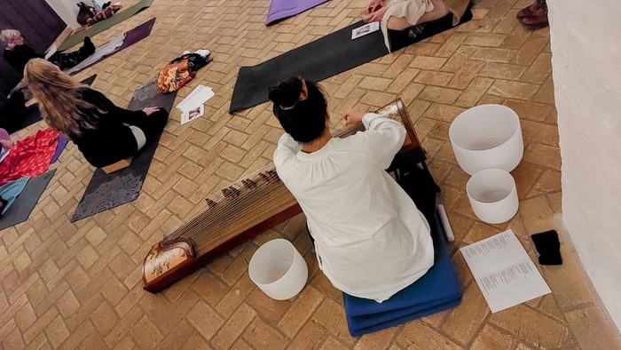 musiker Zhang Yu (Sophia) og yogainstruktør Søs Andresen i aktion under yogagudstjeneste i Haslev Kirke