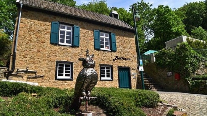 Bethaus der Bergleute in der Sonne mit davor eine Skulptur einer Eule.
