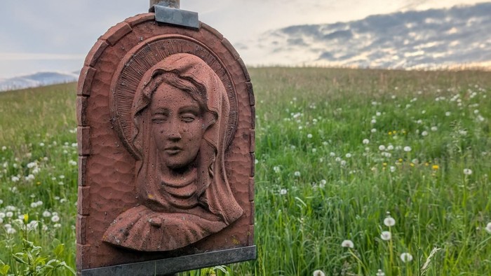 Marienrelief aus Ton auf Blumenwiese