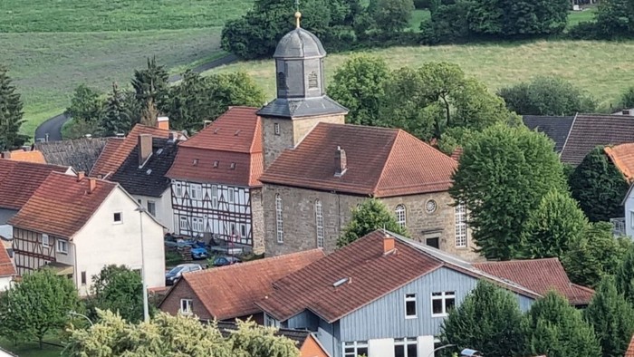 Ein malerisches Dorf mit roten Dächern und einem Kirchturm inmitten von grünen Feldern