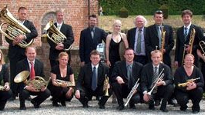 En gruppe musiker poser med instrumenter i en gård.