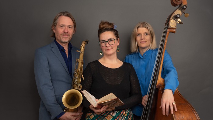 Musikere poserende med saxofon, bog og kontrabas i et professionelt miljø.