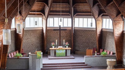 Ein moderner Wohnraum mit hohen Decken und großen Fenstern, eingerichtet mit Holz und grünen Akzenten.