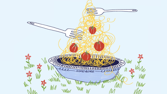Lækkert spaghetti med cherrytomater, der løftes med en gaffel over en græsmark.
