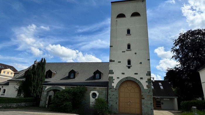 Kirchengebäude mit hohem Turm und Holztür