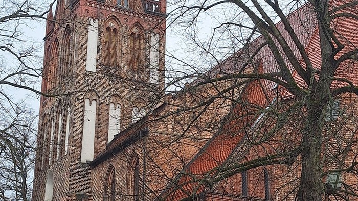 Gothische Backsteinkirche mit hohem Turm und Uhr.
