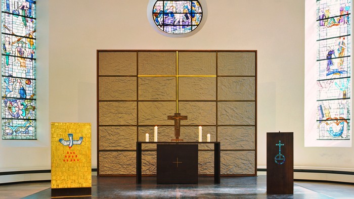 Der Altar in einer Kirche mit farbenfrohen Buntglasfenstern und Kerzenhaltern