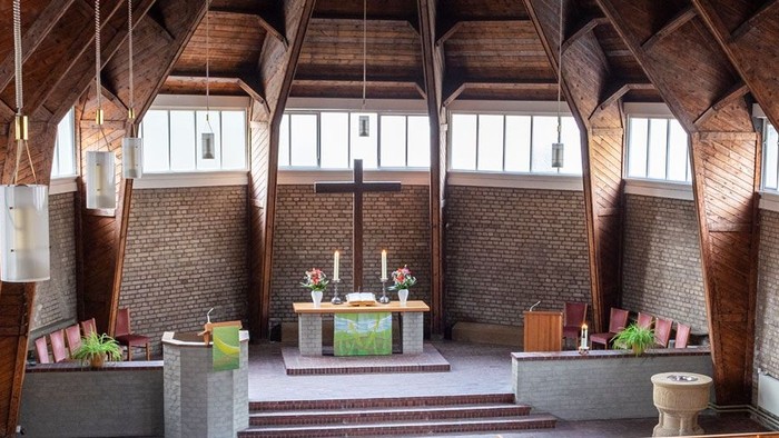Ein moderner Wohnraum mit hohen Decken und großen Fenstern, eingerichtet mit Holz und grünen Akzenten.