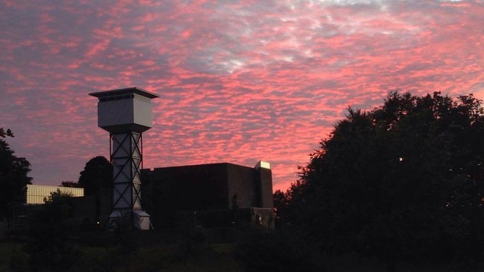 En aftenhimmel med lyserøde skyer over en kirkebygning og kirketårn.