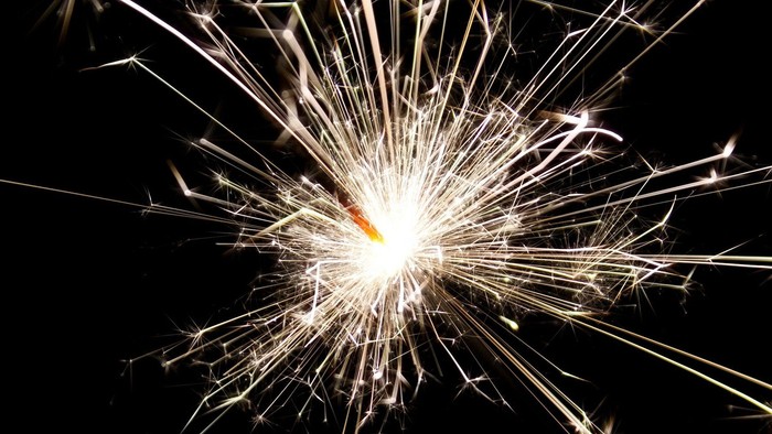 Ein Feuerwerk explodiert hell gegen den schwarzen Nachthimmel.