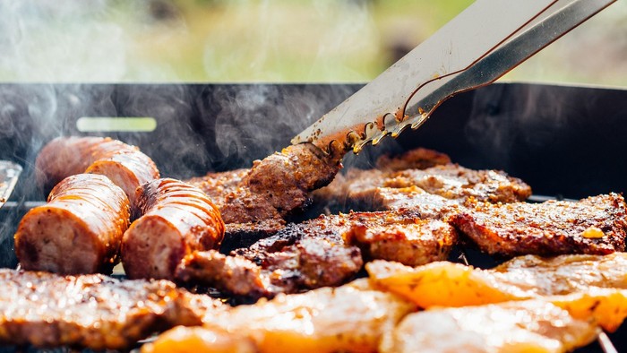 Grill med kødet, pølser og frukt i træske.