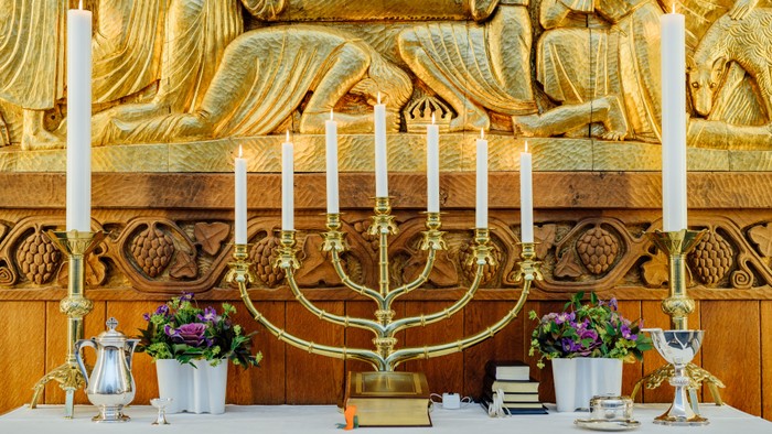 Guld farverede lysestage og blomster i kirke
